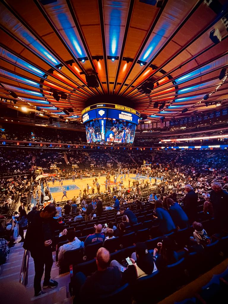 Overhead view of a packed indoor basketball arena with orange lighting