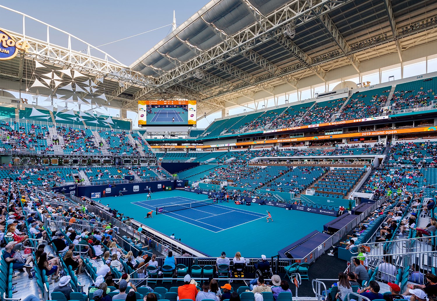 Tennis spectators surrounding a blue court at the Miami Open